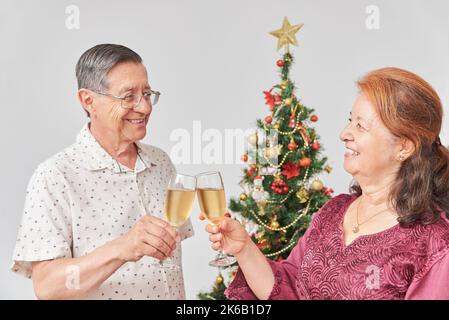 Ein glückliches, älteres hispanische Paar, das zu Weihnachten oder Neujahr toastiert und gemeinsam die Feiertage zu Hause feiert. Stockfoto