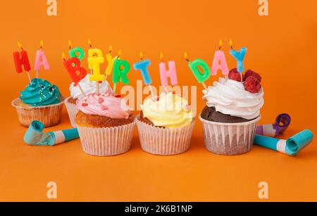 Cupcake mit Geburtstagskerzen auf orangefarbenem Hintergrund Stockfoto