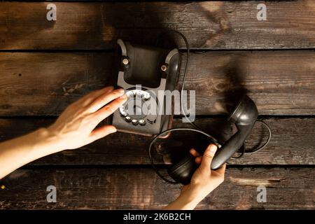 Altes Retro-Telefon schwarz und die Hand der Frau Nahaufnahme, Anruf am Telefon, Technologie Stockfoto