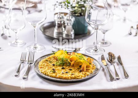 Kreativ zubereitetes Kürbisrisotto, serviert auf einem feierlich zubereiteten Tisch im Hotelrestaurant. Stockfoto