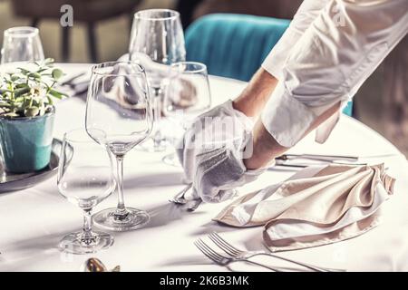 Der Kellner bereitet den Festtisch im Hotelrestaurant zu. Stockfoto