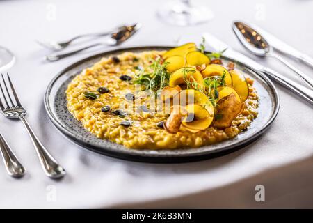 Kreativ zubereitetes Kürbisrisotto, serviert auf einem feierlich zubereiteten Tisch im Hotelrestaurant. Stockfoto