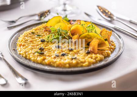 Kreativ zubereitetes Kürbisrisotto, serviert auf einem feierlich zubereiteten Tisch im Hotelrestaurant. Stockfoto