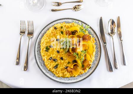 Kreativ zubereitetes Kürbisrisotto, serviert auf einem feierlich zubereiteten Tisch im Hotelrestaurant. Draufsicht. Stockfoto