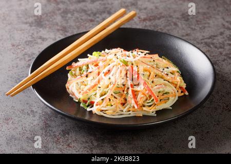 Kani-Salat aus Krabbenfleisch und Julienne-Gemüse, alles in einem süßen, würzigen und cremigen Dressing in der Nähe auf dem Teller auf dem Tisch übergossen. Horizontal Stockfoto