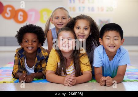 Wir können viel tun, wenn wir vereint sind. Eine Gruppe von Kindern, die in der Klasse auf dem Boden liegen. Stockfoto