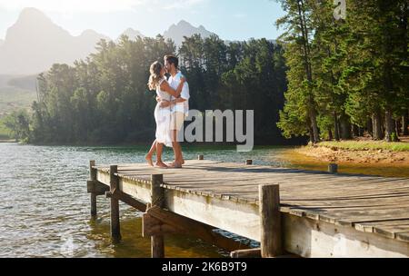 Ein junges Paar tanzt, während es Zeit an einem See verbringt. Stockfoto