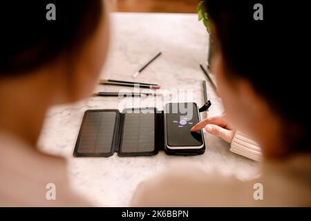 Frau berührt Smartphone-Bildschirm von Tochter zu Hause Stockfoto