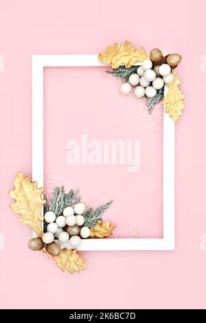 Festlicher Weihnachtshintergrund auf rosa mit weißem Rahmen, Baumschmuck Glitzerkugeln, goldenen Eicheln, Blättern, schneebedeckte Tanne. Minimalistisches Deko-Design Stockfoto