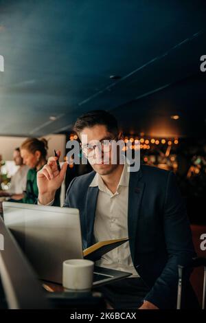 Porträt eines Geschäftsmannes mit Brille, der mit einem Laptop im Hotel sitzt Stockfoto