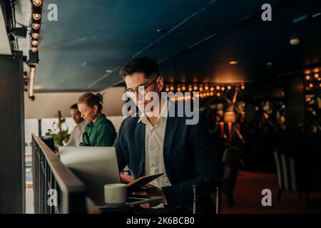 Geschäftsmann, der im Hotel sitzt und an einem Laptop arbeitet Stockfoto