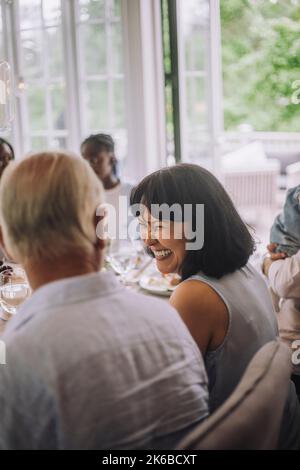 Glückliche Frau, die beim Abendessen auf der Party den Mann ansah Stockfoto