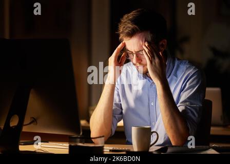 Ich habe mich nicht für diese Art von Stress angemeldet. Ein junger Geschäftsmann, der gestresst aussagt, während er nachts an einem Computer in einem Büro arbeitete. Stockfoto