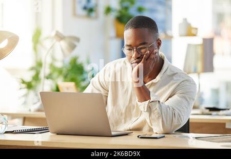 Er braucht eine neue Herausforderung. Ein junger Geschäftsmann, der gelangweilt an seinem Schreibtisch sitzt. Stockfoto