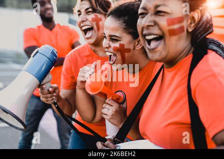 Frauen Fußballfans jubelten beim Fußballspiel im Stadion - Frauen mit gemaltem Gesicht und Megaphon ermutigen ihr Team Stockfoto