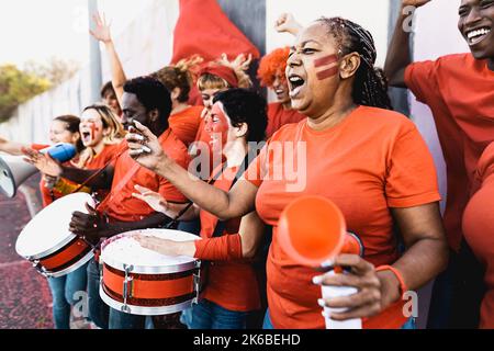 Fußballfans jubelten beim Fußballspiel im Stadion - Menschen mit gemaltem Gesicht und Trommel ermutigen ihr Team Stockfoto