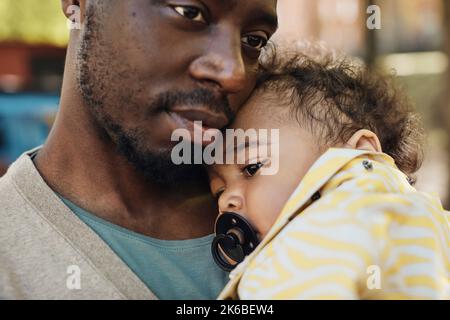 Vater trägt Kleinkind Junge mit Schnuller im Mund Stockfoto