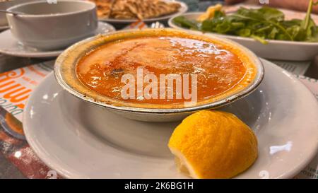 Türkische Suppe Beyran mit Lammfleisch, Reis, gehacktem Knoblauch und Essigsauce serviert mit Salat. Stockfoto