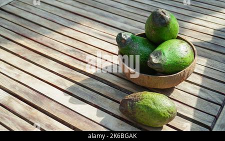 Gruppe reifer Avocados in Bambusschüssel auf Holzboden. Selektiver Fokus. Stockfoto