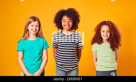 Studio Portrait Aufnahme Von Drei Kinderfreunden Gegen Gelben Hintergrund Stockfoto