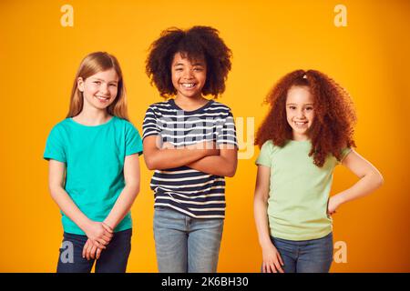 Studio Portrait Aufnahme Von Drei Kinderfreunden Gegen Gelben Hintergrund Stockfoto