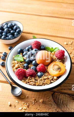 Müslischale mit Beeren und Früchten auf einem Holztisch Hintergrund Stockfoto