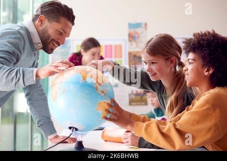 Gruppe Von Multikulturellen Schülern Mit Lehrern Im Klassenzimmer Mit Blick Auf Globe In Geografie-Unterricht Stockfoto