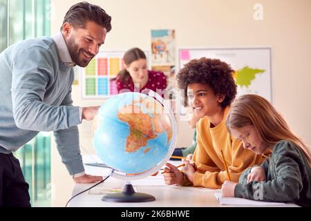 Gruppe Von Multikulturellen Schülern Mit Lehrern Im Klassenzimmer Mit Blick Auf Globe In Geografie-Unterricht Stockfoto