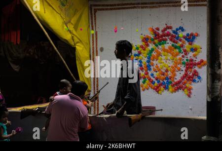 Ein Mann lehrt seinen Sohn im Ballonschießstand mit einem Luftgewehr zielgerichtet schießen Stockfoto