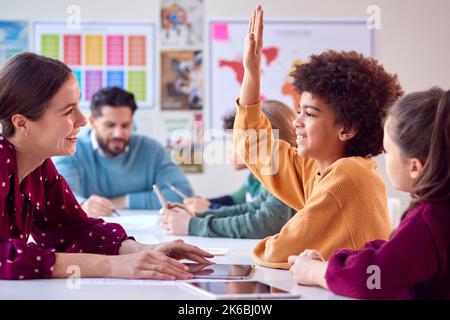 Gruppe Von Multikulturellen Schülern Mit Lehrern Im Klassenzimmer, Die Hand Auflegen, Um Die Frage Zu Beantworten Stockfoto