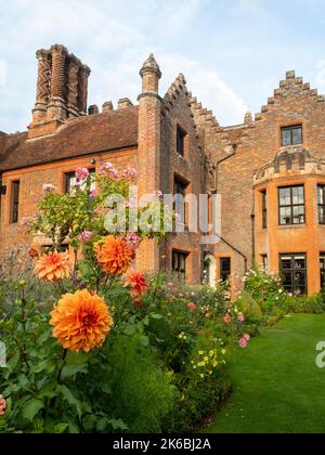 Chenies Manor und Garten umgeben von bunten Dahlien im Oktober. Dahlia 'Great Herkules' Bronze orange blüht über dem Rest und Rosa 'Ballerina'. Stockfoto