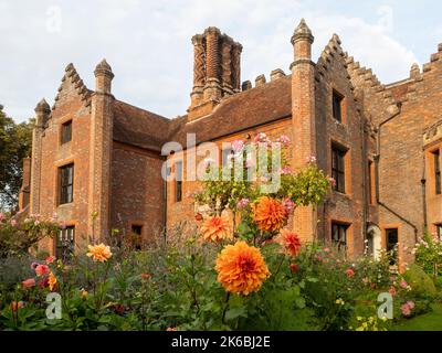 Chenies Manor und Garten umgeben von bunten Dahlien im Oktober. Dahlia 'Great Herkules' Bronze orange blüht über dem Rest und Rosa 'Ballerina'. Stockfoto