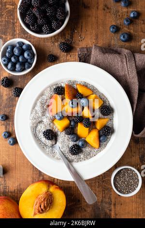 Vegane Chia Pudding Schale Mit Beeren Und Pfirsich Auf Holztisch Hintergrund, Ansicht Von Oben Stockfoto