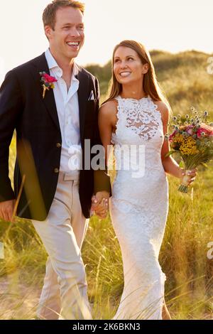 Romantisches Ehepaar Feiert Strandhochzeit Spaziergang In Dunes Zusammen Stockfoto
