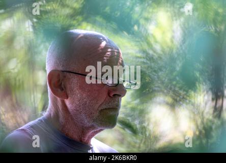 Porträt eines älteren kahlen Mannes mit grauem Bart und Lesebrille in der Natur Stockfoto