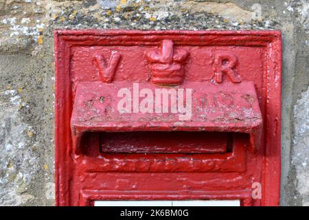 Nahaufnahme der rot bemalten britischen Royal Mail Briefkasten draußen in einer Straße, mit Queens Krone und Initialen V R. Briefkasten ist der britische Monarch Victoria Stockfoto