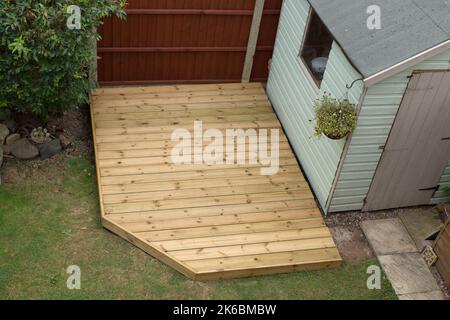 Nahaufnahme der neuen Holzterrasse, die gerade in einem Garten an einem Rasen und Schuppen gebaut wurde. Der Garten ist im Herbst ein heimisches Stück Boden außerhalb eines Hauses Stockfoto