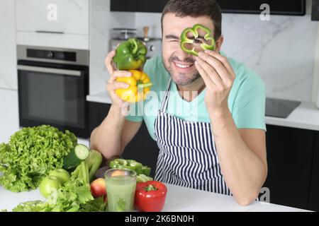 Mann spielt mit grünen Paprika in der Küche Stockfoto