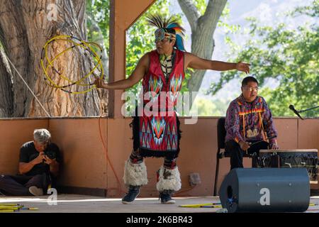 Navajo Native American Hoop Dancer in Regalia, die auf einem Festival in Moab, Utah, auftreten. Dahinter ç ein Schlagzeuger des Sängers. Stockfoto