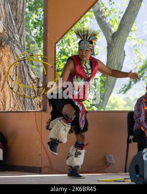 Navajo Native American Hoop Dancer in Regalia, die auf einem Festival in Moab, Utah, auftreten. Dahinter ç ein Schlagzeuger des Sängers. Stockfoto