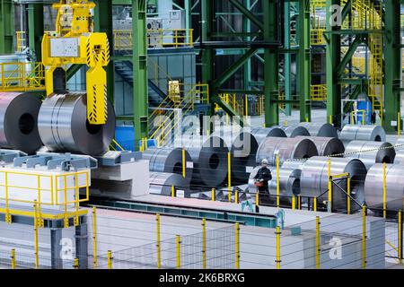 Dortmund, Deutschland. 13. Oktober 2022. Ein Mitarbeiter verlegt Stahlrollen mit einem Kran in die neue Heißlackierlinie (FBA 10) am Standort thyssenkrupp-Westfalenhütte. Mit dieser Investition stärkt das Unternehmen seine Position als führender deutscher Flachstahlhersteller. Quelle: Rolf Vennenbernd/dpa/Alamy Live News Stockfoto