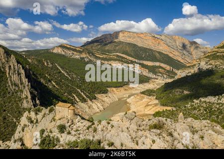 Eremitage von La Pertusa vor dem Montsec und der Mont-rebei-Schlucht mit dem fast trockenen Canelles-Stausee. La Noguera, Lleida, Katalonien, Spanien Stockfoto