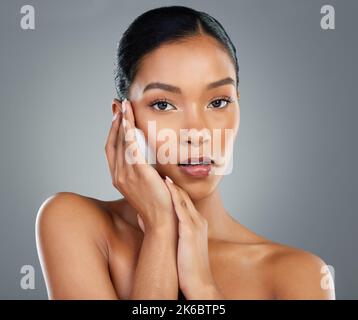 Aufrechterhaltung einer gesunden Hautpflege Routine. Eine schöne junge Frau posiert vor einem grauen Hintergrund. Stockfoto