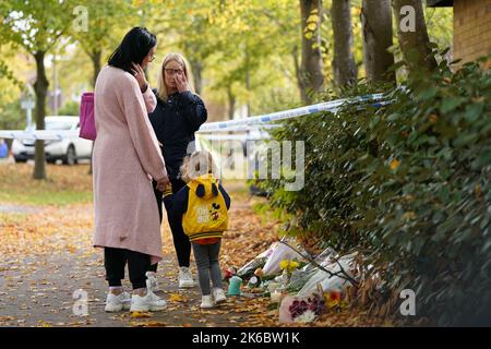 Eine Gruppe von Menschen betrachtet die am Tatort in Loxbeare Drive, Furzton, Milton Keynes zurückgebliebenen Ehrungen, wo die Polizei bei gerichtlichen Untersuchungen menschliche Überreste auf der Suche nach dem vermissten Teenager Leah Croucher identifiziert hat, der im Februar 2019 zu Fuß zur Arbeit verschwand. Beamte der Polizei von Thames Valley begannen am Montag, das Haus nach einem Tipp eines Bürgers zu durchsuchen und starteten eine Morduntersuchung, als sie einen Rucksack und andere persönliche Gegenstände von Frau Croucher fanden. Bilddatum: Donnerstag, 13. Oktober 2022. Stockfoto