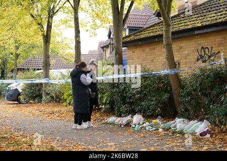 Eine Gruppe von Menschen betrachtet die am Tatort in Loxbeare Drive, Furzton, Milton Keynes zurückgebliebenen Ehrungen, wo die Polizei bei gerichtlichen Untersuchungen menschliche Überreste auf der Suche nach dem vermissten Teenager Leah Croucher identifiziert hat, der im Februar 2019 zu Fuß zur Arbeit verschwand. Beamte der Polizei von Thames Valley begannen am Montag, das Haus nach einem Tipp eines Bürgers zu durchsuchen und starteten eine Morduntersuchung, als sie einen Rucksack und andere persönliche Gegenstände von Frau Croucher fanden. Bilddatum: Donnerstag, 13. Oktober 2022. Stockfoto