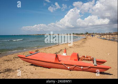 Portopalo, Italien - 09-17-2022: Schöner Strand mit Sand, türkisfarbenem und grünem Wasser ist ein roter Patino im Vordergrund in Portopalo di Capo Passero Stockfoto