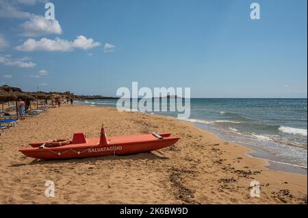 Portopalo, Italien - 09-17-2022: Schöner Strand mit Sand, türkisfarbenem und grünem Wasser ist ein roter Patino im Vordergrund in Portopalo di Capo Passero Stockfoto