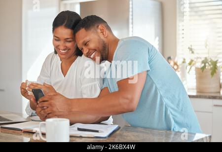 Baby, das solltest du sehen. Ein Mann zeigt seiner Frau etwas auf seinem Handy, während er zu Hause sitzt. Stockfoto