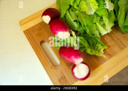 Frischer Rettich und Salat auf einem Schneidebrett Stockfoto