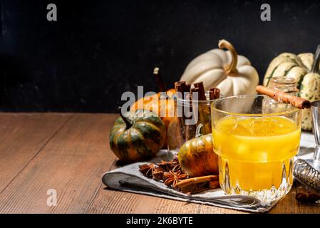 Hausgemachter alkoholischer Kürbis-Zimt-Cocktail, erfrischender eisgekühlter Kürbis-Gewürz-altmodischer Cocktail, Holzküchentisch im Hintergrund Kopierraum Stockfoto